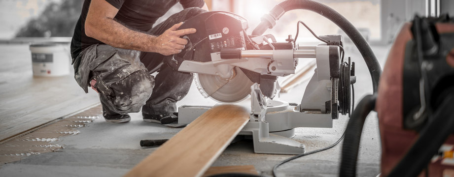 Handwerker schneidet Holzdiele mit der Kapps&auml;ge auf der Baustelle und die Sp&auml;ne werden direkt vom Staubsuager abgesaugt