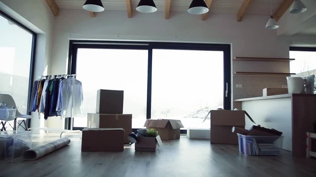 Moving boxes, clothes rack and small furniture on the floor in new home.