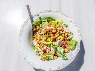 A bowl of ceasar salad on a marble table