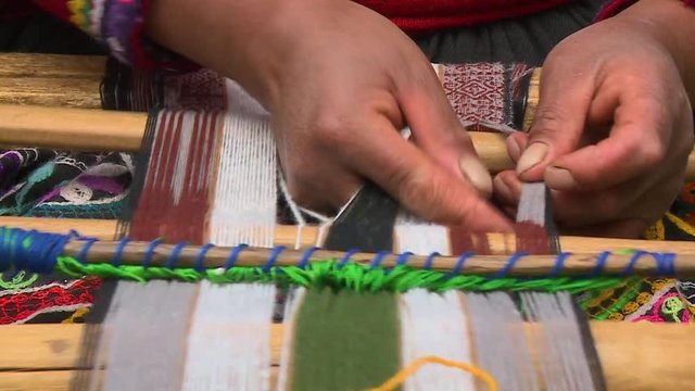 Extreme, close-up, high-angle still shot of a peruvian woman weaving complicated fabric pattern using a hand loom, Sacred Valley, Peru