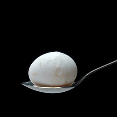 BIG SPOON WITH AN EGG ON A DARK BACKGROUND