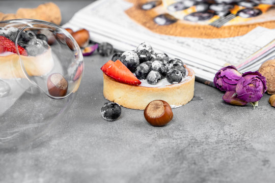 Blueberry and strawberry shortcake. There are hazelnuts, roses and wine corks on the table. Stone background.