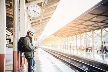 Fototapeta premium Travel man wait train at platform - people vacation lifestyle activities at train station transportation concept