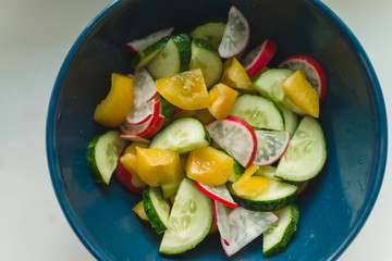 Fresh summer salad with radishes, cucumbers and yellow peppers.