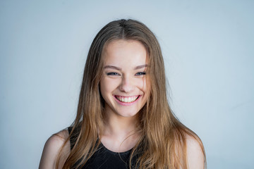 Fototapeta premium Happy girl face portrait. Close up portrait of young cheerful beautiful girl with long hair in casual shirt smiling looking in camera with happy face expression.