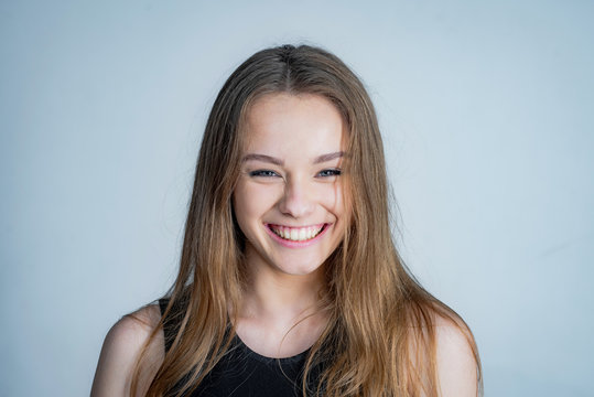 Happy girl face portrait. Close up portrait of young cheerful beautiful girl with long hair in casual shirt smiling looking in camera with happy face expression.