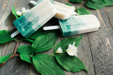Spirulina ice cream Colored ice cream with healthy additives Spirulina coconut milk ice cream next to green spirulina powder and flowers on a dark background Top view Copy space Selective focus