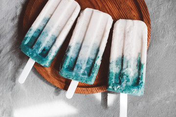 Colored ice cream with healthy superfood Spirulina coconut milk ice cream next to green spirulina powder on a on light gray background Top view Copy space Selective focus