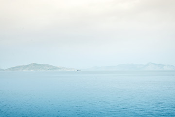 Foggy mountain misty islands covered with fog, calm sea lake landscape background, sunlight in cloudy sky scenery morning weather,