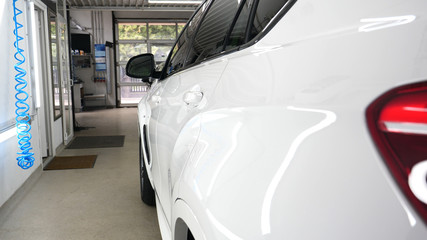 A man in the garage (car service) Checks the car alarm and then goes off (comes in) turning off (turning on) the lights behind him. Concept of: Auto garage, Security.	