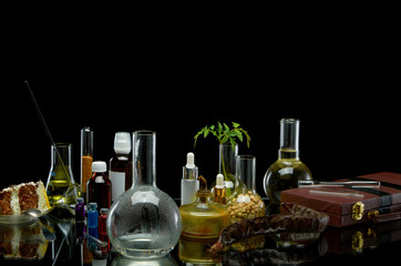 Medical jars with reagents and a plant with a leather suitcase on a black background
