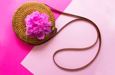  straw stylish modern women summer bag and peony flower on a pink background. Summer vacation concept