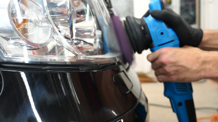 Fototapeta premium A professional bodywork and headlamp polishing worker will transport the car after painting or preparing for sale. Concept of: Freshen cars, Automotive center, Service, Professional. 