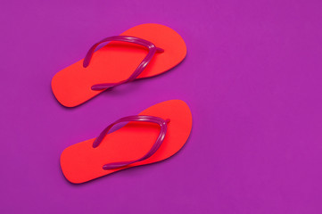 Coral flip flops on purple background. Flat lay, top view, copy space. Creative Summer Vacation...