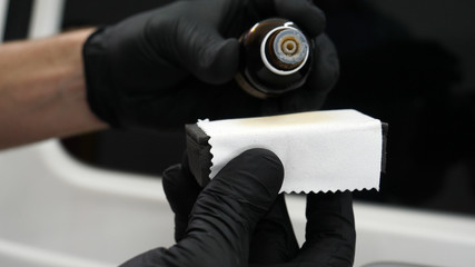 The professional worker holds a white sponge in his hand, applies liquid, auto repair shop, car...