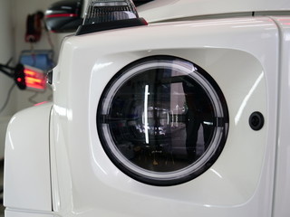 Infrared drying of car body parts after applying putty and paint on a white off-road vehicle in the body repair shop with red lanterns in the working environment. Concept of: Car Ceramic, Slow Motion.