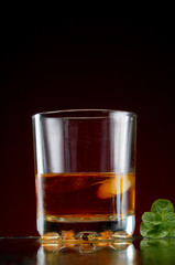 Glass with alcohol in a transparent glass with ice and mint on a red background