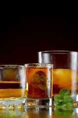 Alcoholic drink in glasses with ice and mint on red background