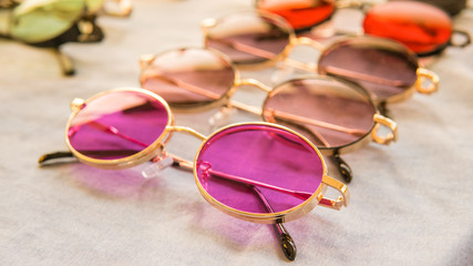 Set of colorful sunglasses for sale in a store. Different sunglasses on light coloured background