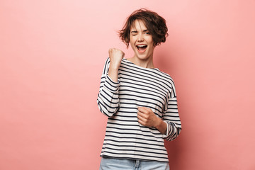 Woman posing isolated over pink wall background make winner gesture.