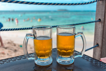 Dois canecos de chope na praia do Caribe