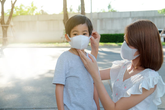 Asian Young Mother Wearing Protective PM2.5 Mask For Her Son At Outdoor