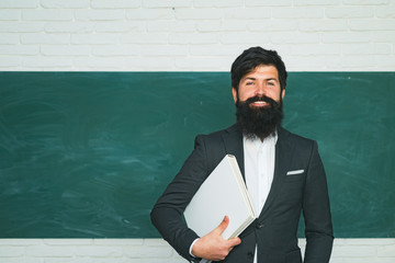 Tutoring. Back to school and happy time. Bearded professor at school lesson at desks in classroom....