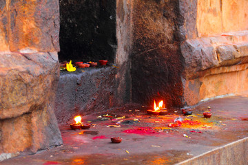 Colorful image of stone Hindu shrine with burning candles, color powder and joss sticks in Sri...
