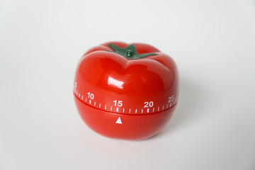 Close up view of mechanical tomato shaped kitchen clock timer for cooking & studying. Used for pomodoro technique for time and productivity management. Isolated on white background, set at 15 minutes.