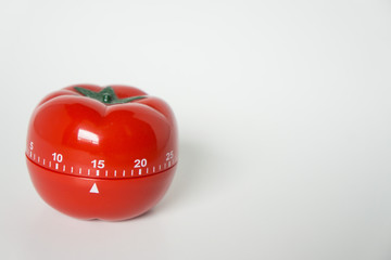 Close up view of mechanical tomato shaped kitchen clock timer for cooking & studying. Used for pomodoro technique for time and productivity management. Isolated on white background, set at 15 minutes.