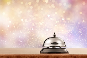 Vintage hotel reception service desk bell on wooden table with abstract background