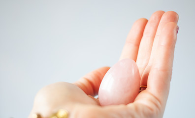 woman holding in hand a vaginal (yoni) egg. Rose quartz crystal jade egg. Copy space