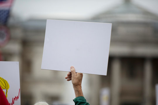 A person holding a blank protest banner at a political rally
