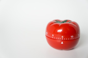 Close up view of mechanical tomato shaped kitchen clock timer for cooking & studying. Used for pomodoro technique for time and productivity management. Isolated on white background, set at 5 minutes.