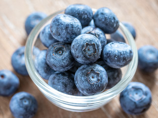 Blueberries in a glass bowl on wooden table and texture, fresh fruit with water droplet