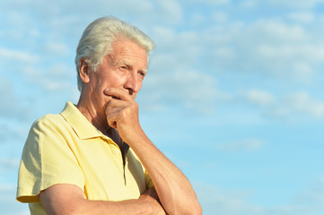 Thinking senior man posing in summer park