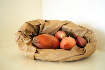 Raw onions in a brown paper bag