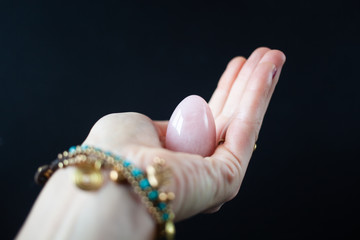 woman holding in hand a vaginal (yoni) egg. Rose quartz crystal jade egg. Copy space