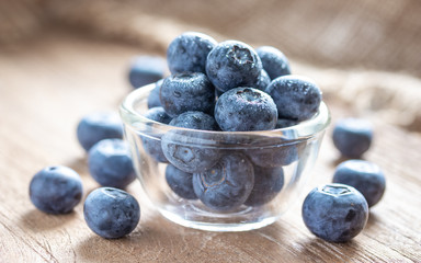 Blueberries in a glass bowl on wooden table and texture, fresh fruit with water droplet