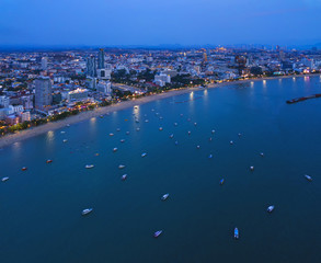 Aerial view of boats in Pattaya sea, beach at night, and urban city with blue sky for travel...