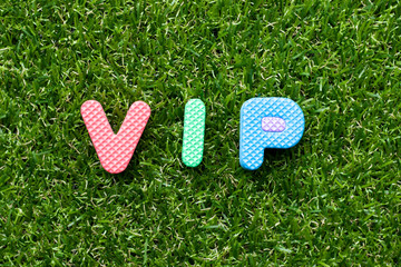 Toy foam letter in word VIP (abbreviation of very important person) on green grass background