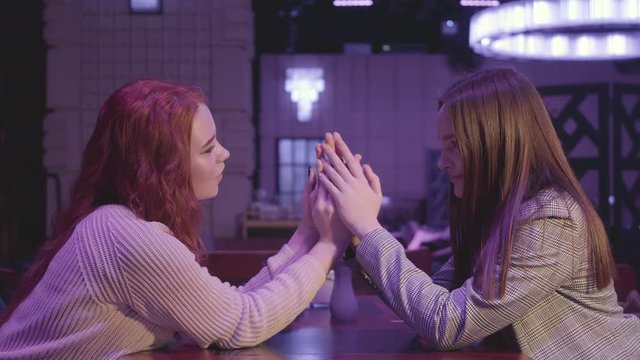 Portrait of two cute lesbian couple holding hands in blue light. LGBT love and relationship concept