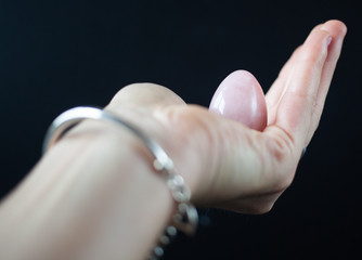 woman holding in hand a vaginal (yoni) egg. Rose quartz crystal jade egg. Copy space