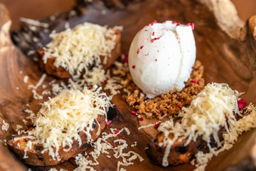 ice cream with grated cheese and feminine caramel. served on a wooden plate
