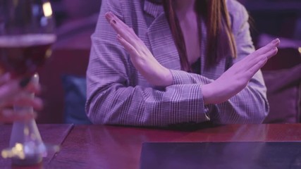 Female hand holding glass with alcohol cocktail close up. Unrecognizable woman making refusal gestures, she does not want to drink more alcohol. Unhealthy lifestyle