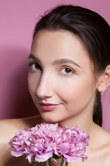 Young beautiful woman with flower on pink background.