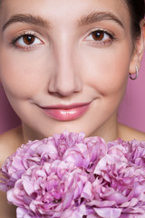 Young beautiful woman with flower on pink background.