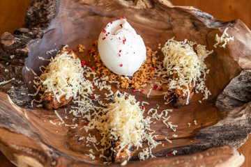 ice cream with grated cheese and feminine caramel. served on a wooden plate