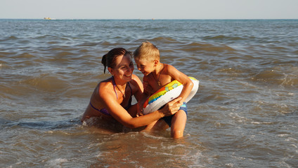 Mother and sun swimming in the sea. Summer vacation on the sea beach.