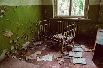 Old broken children beds in kindergarten, nursery school. Destroyed abandoned ghost city Pripyat...